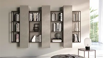 Libreria Grafic sospesa in metallo brunito con ripiani in laccato opaco ortensia e Pensili Modulo con ante in cemento pietra.